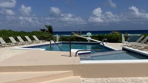 Un área de piscina con múltiples sillones reclinables y vistas al océano.