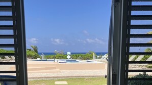 Vista desde una habitación con piscina, incluyendo una mesa de billar azul y una zona junto a la piscina con sillones de descanso.
