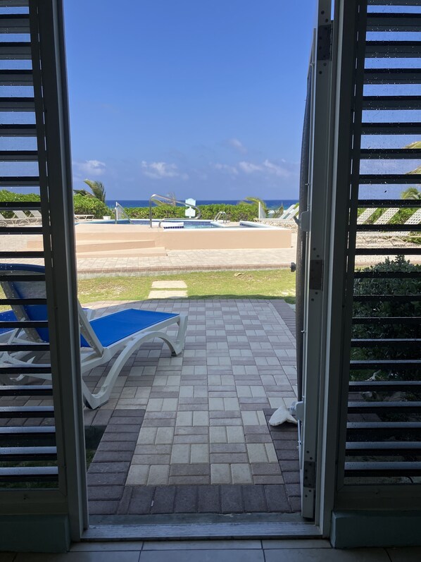 A view from a room with a pool, including a blue pool table and a poolside area with lounge chairs.