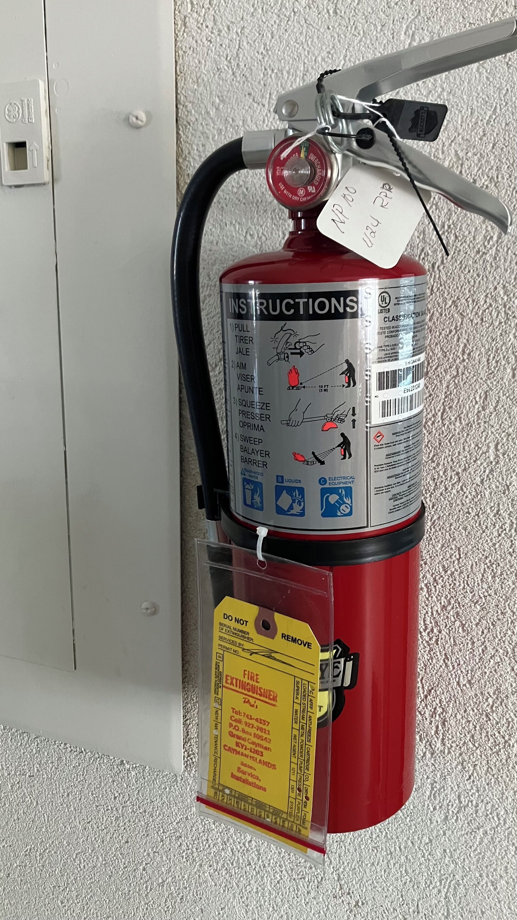 A fire extinguisher mounted on a wall with instructions and a tag.