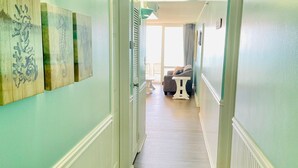 A hallway with teal walls and wooden floors, leading to a seating area with a view of the outdoors. - Ocean City 2BR Oceanfront Condo - Bay Views, Pools, Ice Rink & More! (Ocean City)