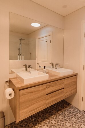 A bathroom with two sinks, a large mirror, and a wooden vanity.