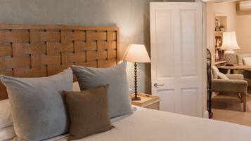 A bedroom with a large bed, a wooden headboard, a ceiling fan, a nightstand, a chair, and a door leading to another room.