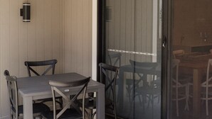 Eine Terrasse mit Tisch und Stühlen, eine Glasschiebetür und eine Fußmatte.