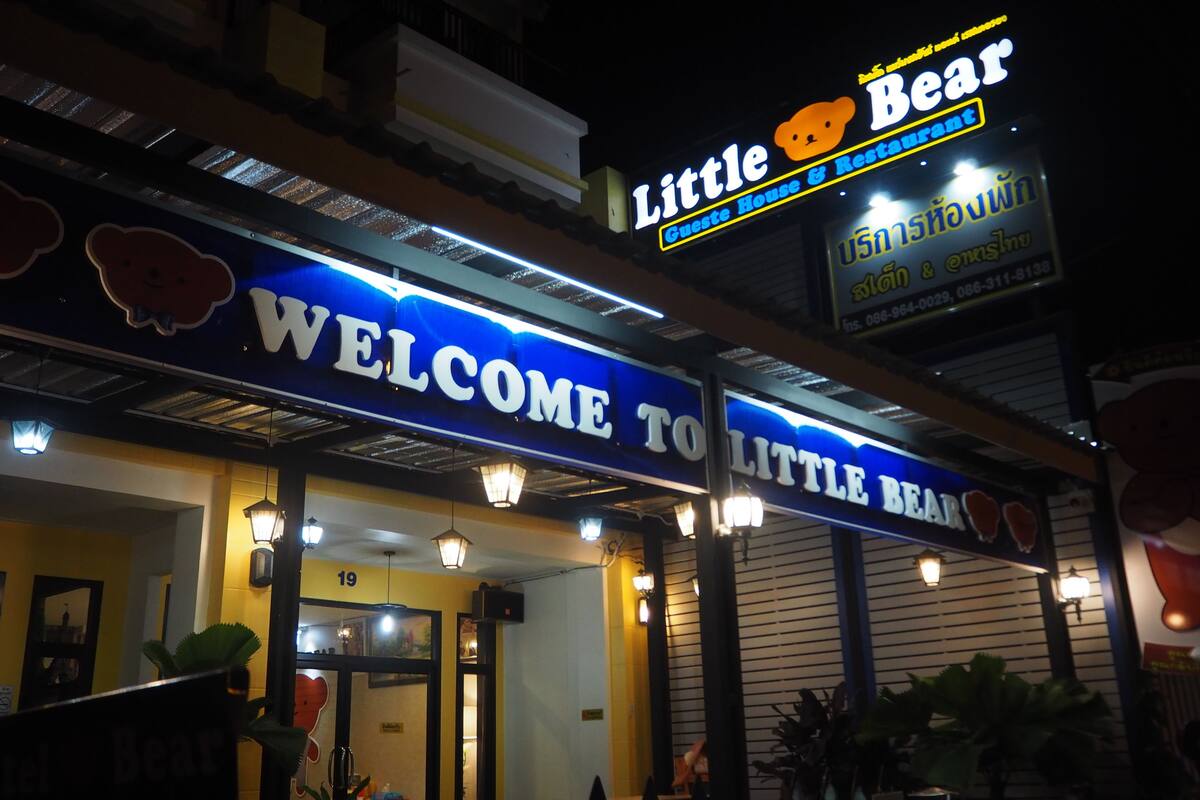 Ein Gebäude mit einem Schild, auf dem „Little Bear Guest House & Restaurant“ und ein Schild mit der Aufschrift „Willkommen im Little Bear“ stehen.