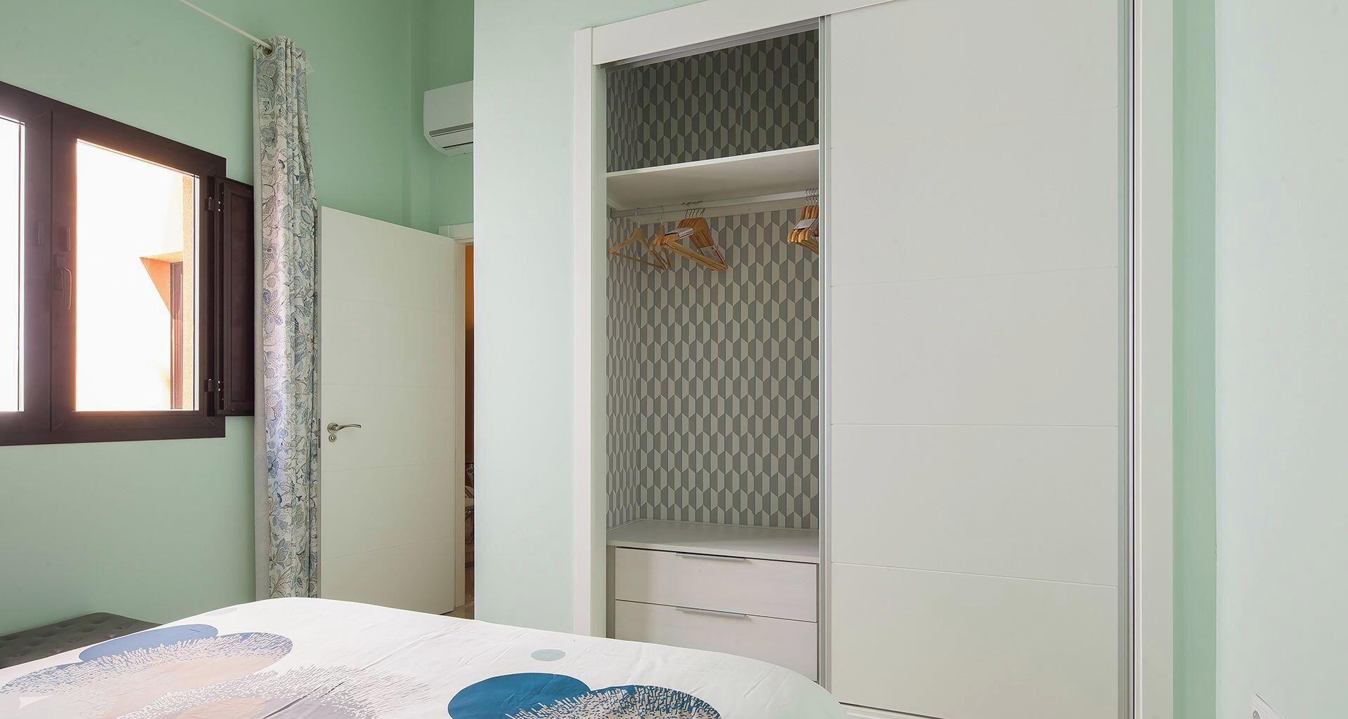 A bedroom with a bed, a wardrobe, and a window.