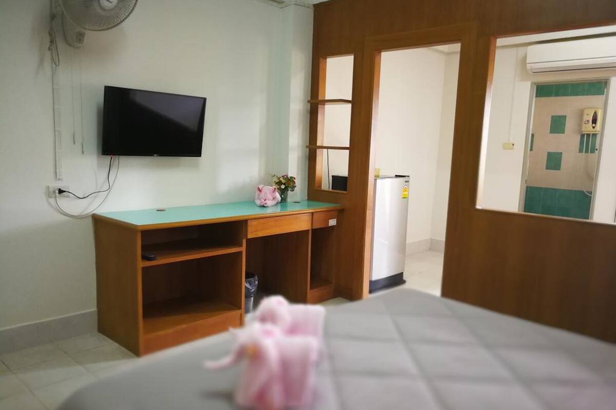 Una habitación de hotel con cama, escritorio, televisión, refrigerador y vistas al exterior.