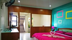 Quarto de hotel com cama, escrivaninha, espelho e janela com cortinas.
