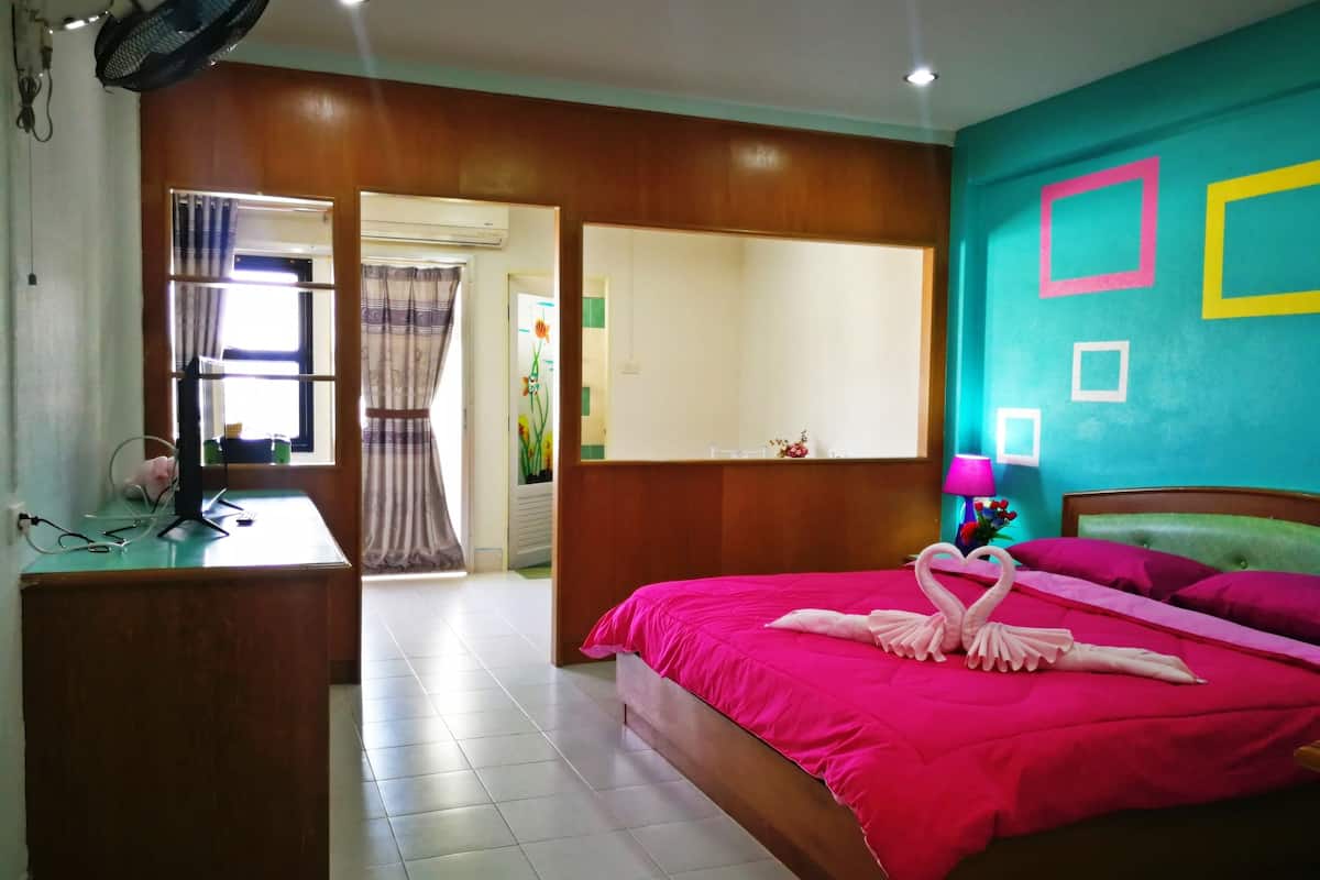 Una habitación de hotel con una cama, un escritorio, un espejo y una ventana con cortinas.
