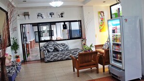 Uma sala de estar com sofá, cadeiras, geladeira e espaço de jantar.
