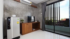 Una sala de estar moderna con aire acondicionado integrado, un mueble de madera, un televisor de pantalla plana y un ventanal corredero que da a un balcón.
