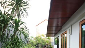 Una casa moderna con terraza de madera, sendero de piedra y abundante vegetación.