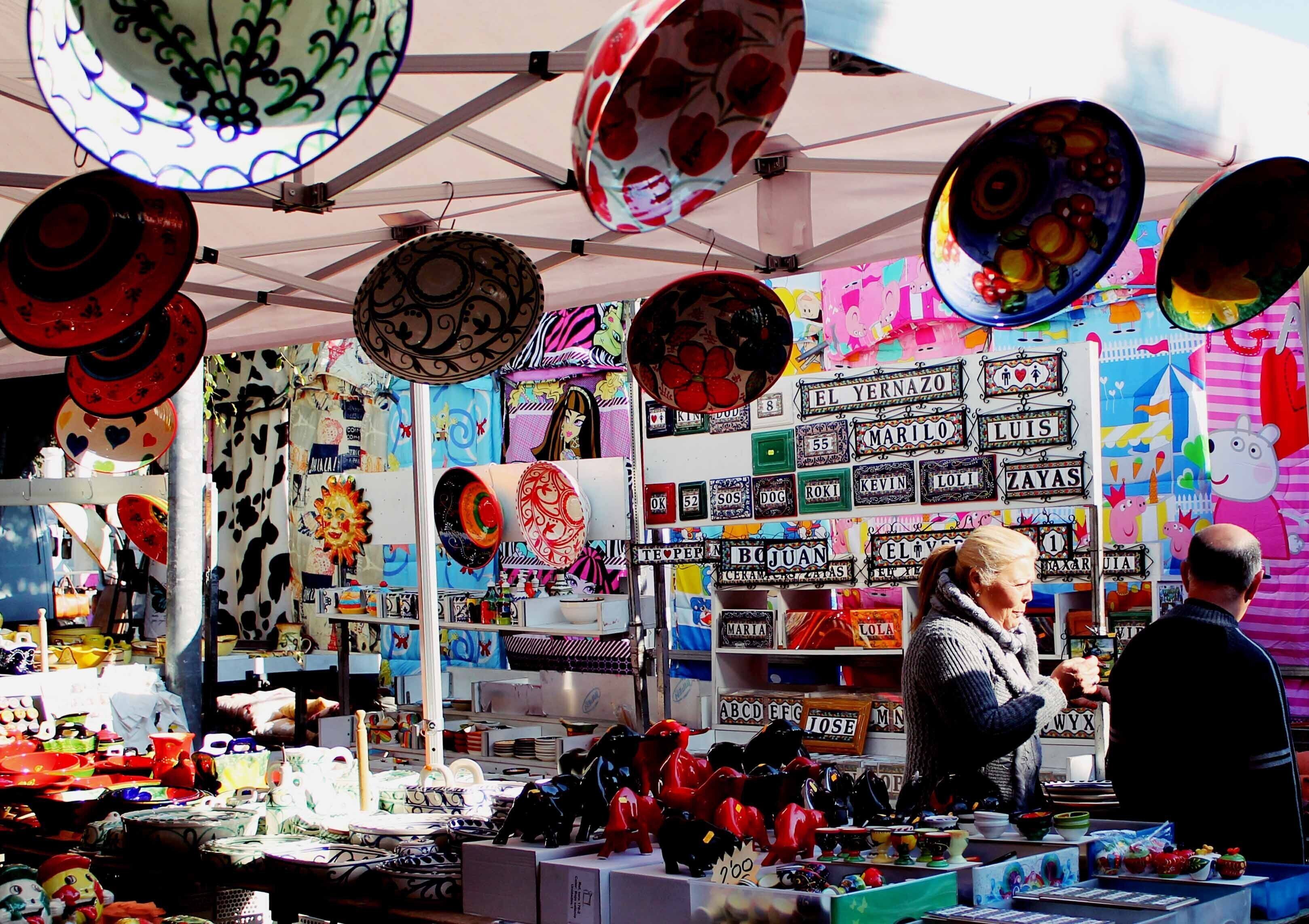 Un étal de marché où sont vendus divers articles, notamment des assiettes et des objets de décoration.