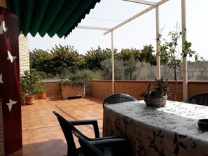 Eine Terrassengruppe mit Tisch und Stühlen, umgeben von Blumentöpfen und einer Ziegelmauer.