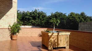 Un patio exterior con una maceta de bambú, una planta en maceta y un muro de ladrillo.