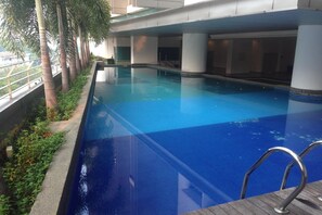 Une piscine intérieure à l’eau d’un bleu cristallin, entourée de palmiers et de piliers en béton.
