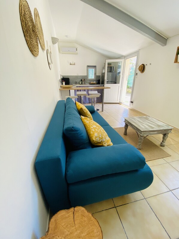 A living room with a blue sofa, a wooden coffee table, and a kitchen in the background.