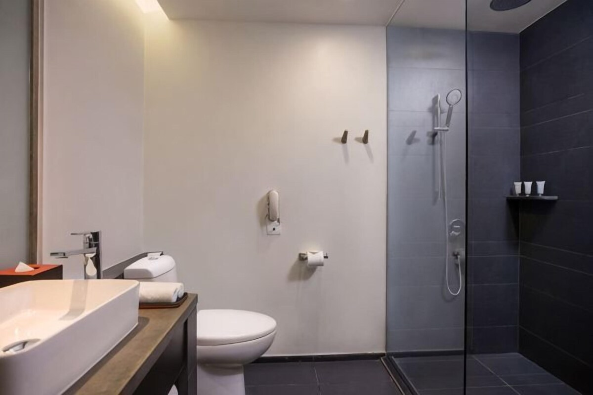 A modern bathroom with a toilet, shower, and sink.
