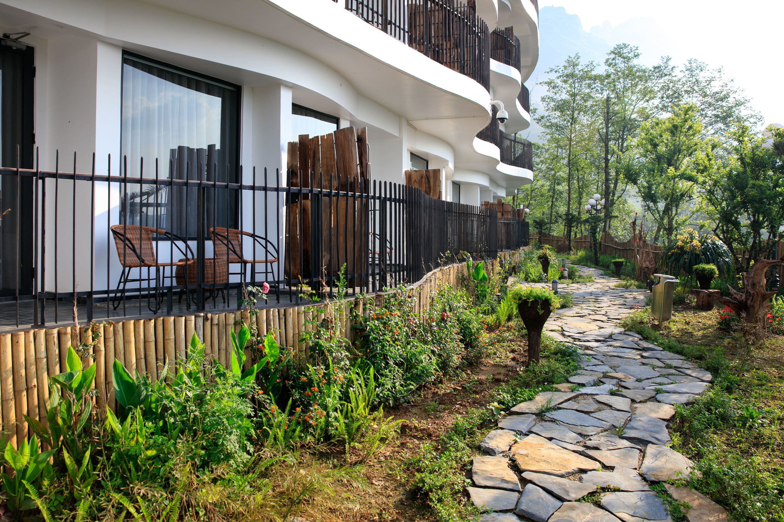 A modern building with a balcony, outdoor seating, and a stone pathway.