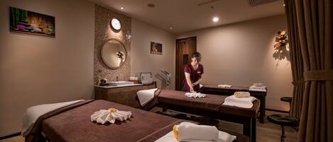 A spa room with two massage tables, a sink, and a mirror.