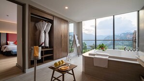 Quarto de hotel moderno com uma grande janela, banheira e guarda-roupa de madeira.