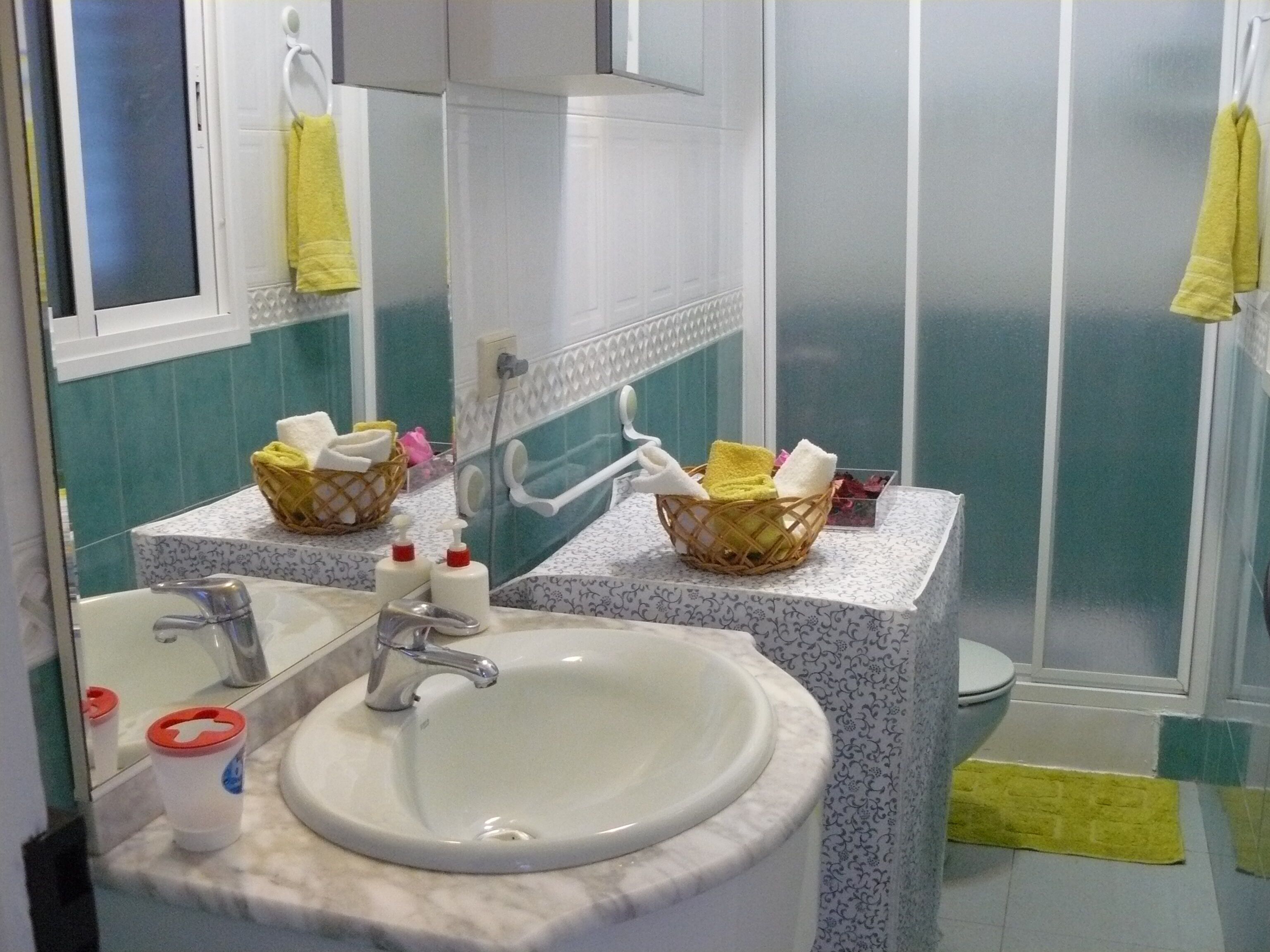 A bathroom with a white sink, two baskets on the counter, and a shower area.