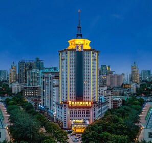 Ein Hochhaus-Hotel mit einem markanten Turm, umgeben von anderen Gebäuden und Grünflächen.