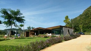 A modern house with a covered patio, a lawn, and a dirt path. - Rabbit Hill Cafe and Resort @ Khao Yai (Pak Chong)