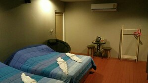 A hotel room with two beds, a small table with a kettle, a chair, and a coat rack. - Rabbit Hill Cafe and Resort @ Khao Yai (Pak Chong)