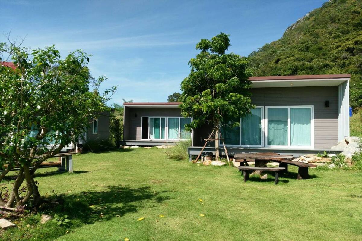 A modern two-story house with large windows, a well-maintained lawn, and a picnic table.