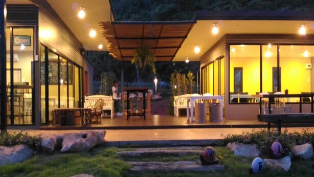 A modern building with a patio area, outdoor seating, and a well-maintained garden. - Rabbit Hill Cafe and Resort @ Khao Yai (Pak Chong)