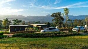 A modern house with a small garden, a car, and a view of distant mountains. - Rabbit Hill Cafe and Resort @ Khao Yai (Pak Chong)