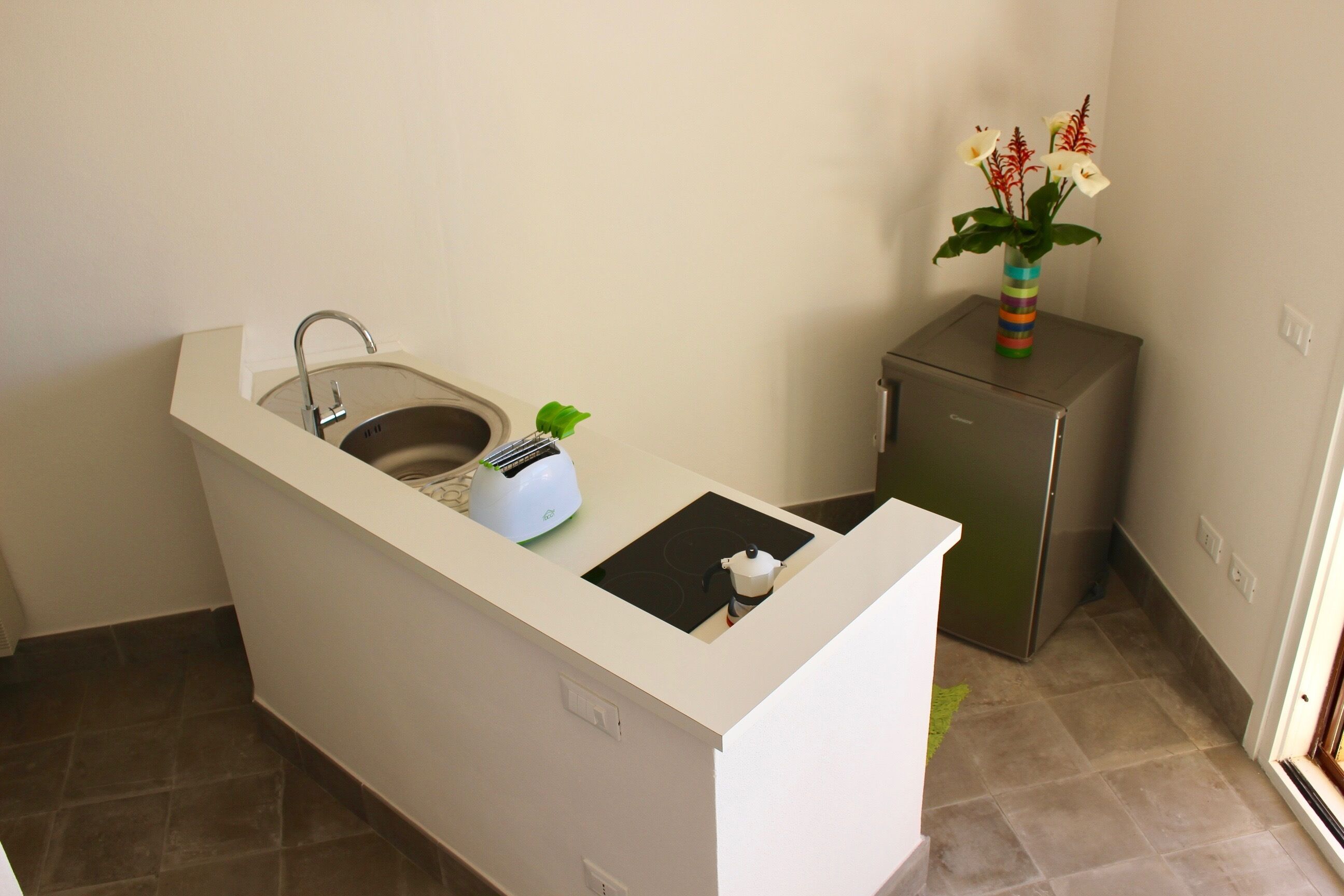 A compact kitchen with a sink, a toaster, and a small refrigerator.