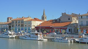 Ein Yachthafen mit vertäuten Booten, eine Kirche mit einem Kirchturm und Gebäude mit Geschäften und Restaurants.