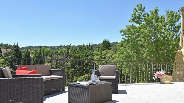 Ein Patio mit Gartenmöbeln aus Rattan, einem Tisch und einem Blumentopf.