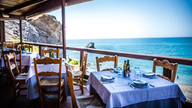 Un restaurante frente al mar, con mesas dispuestas para comer, con vista al océano.