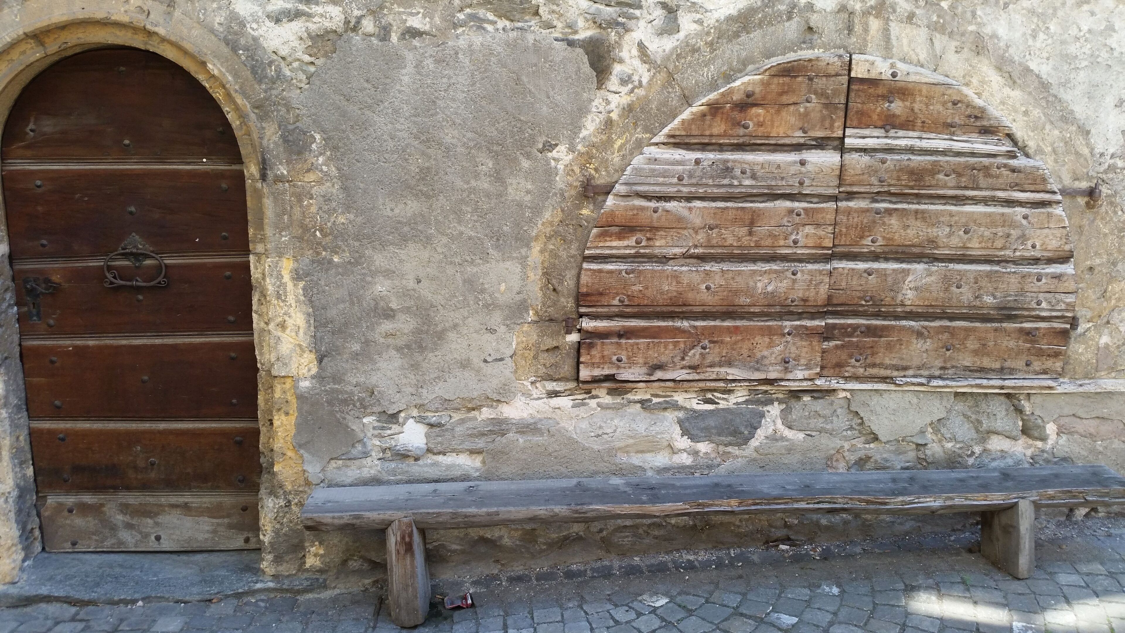 A rustic stone wall with a wooden door and bench.