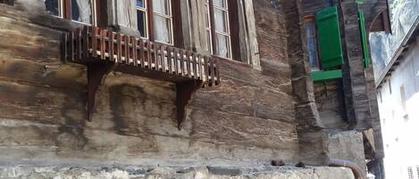 A rustic wooden building with multiple windows, a balcony, and a stone archway.