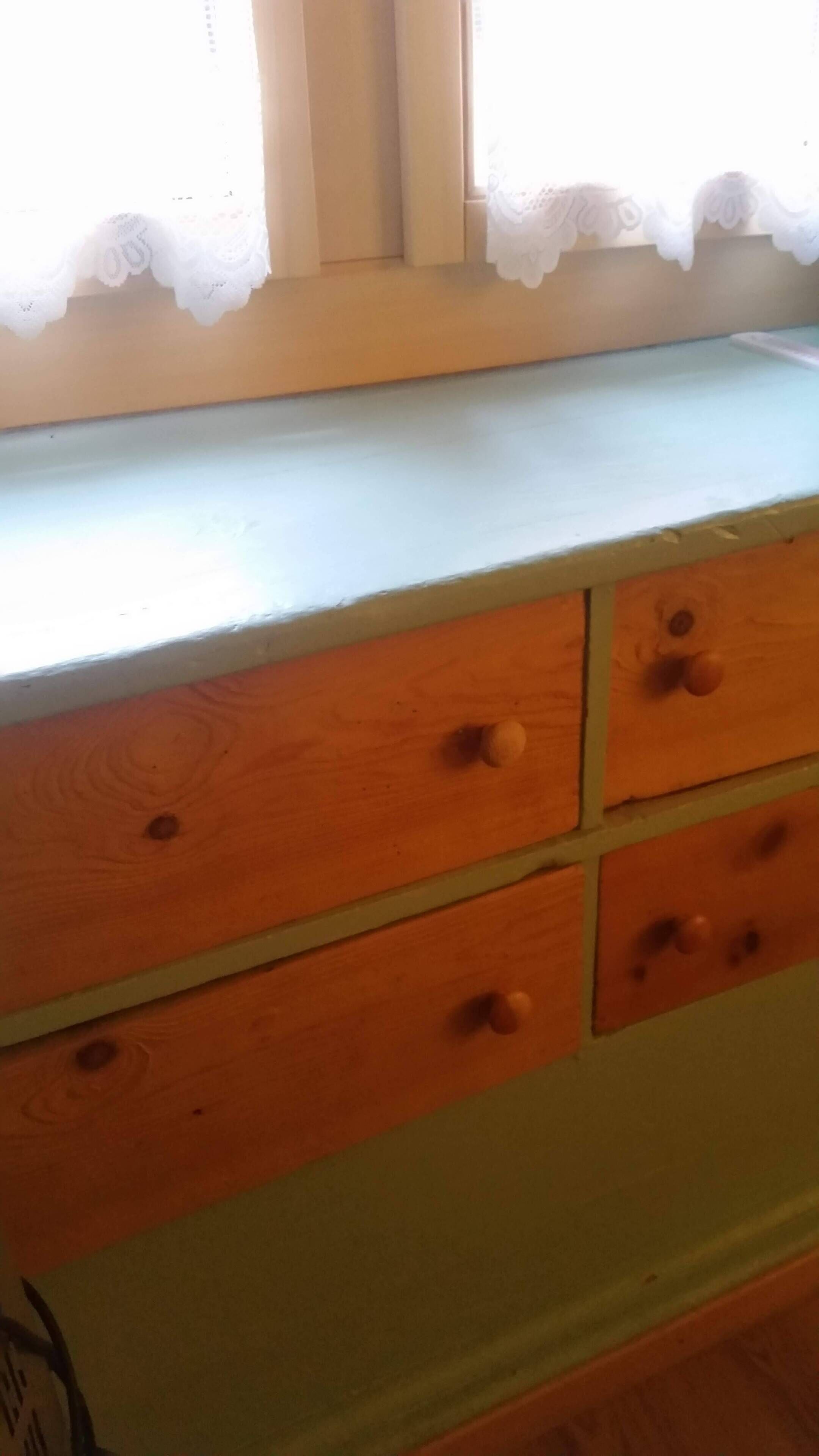 Une commode en bois avec quatre tiroirs et un plateau de couleur claire.