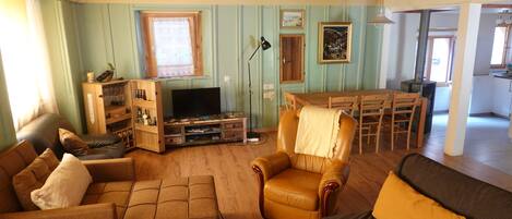 Un salon comprenant un canapé, des fauteuils, une table basse, un téléviseur et un meuble en bois.