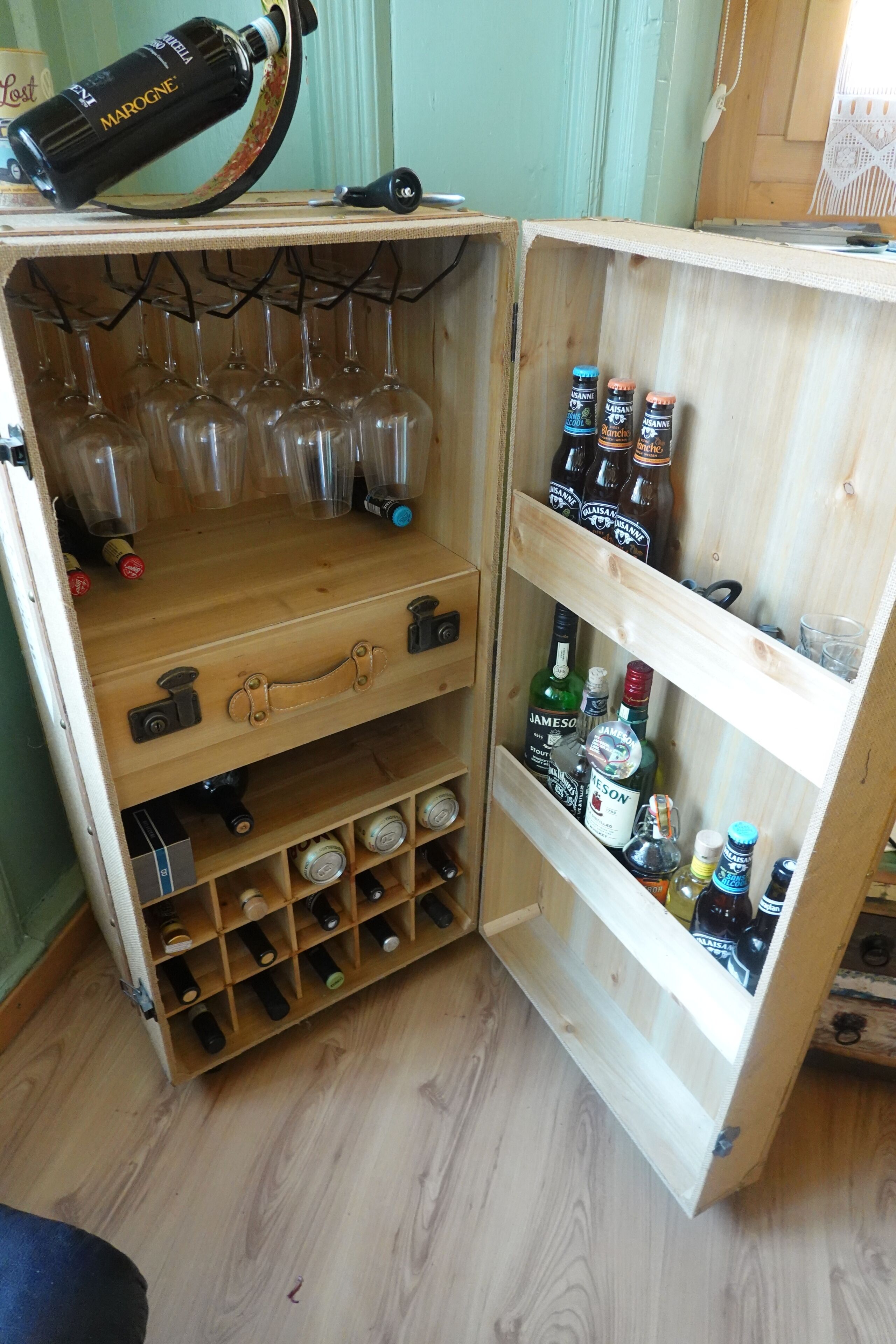 Una botellera de madera con botellas de vino y copas.