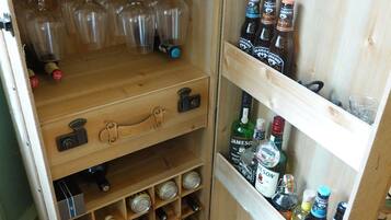 Una botellera de madera con botellas de vino y copas.