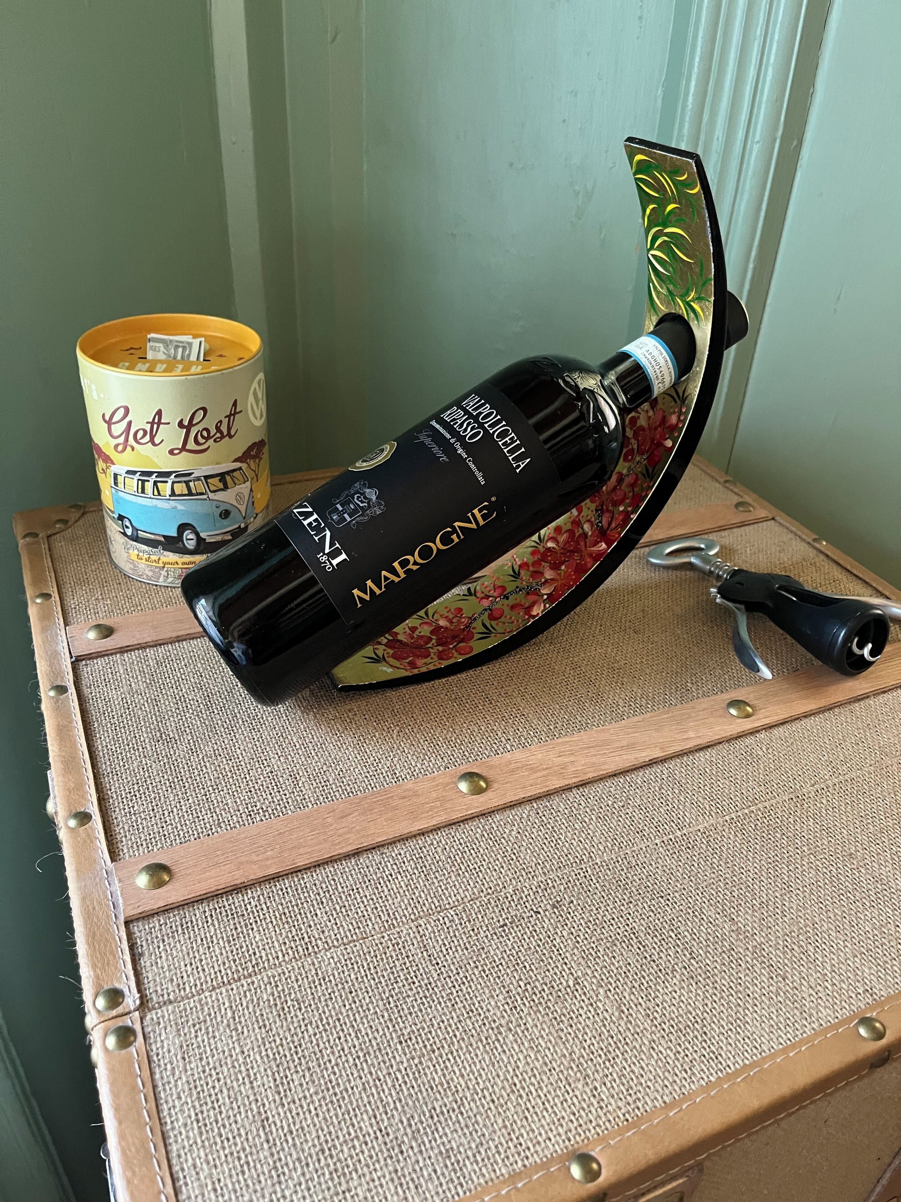 A bottle of wine on a suitcase with a key attached.