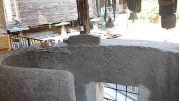 A rustic outdoor area with a concrete structure, wooden beams, and a metal bell.