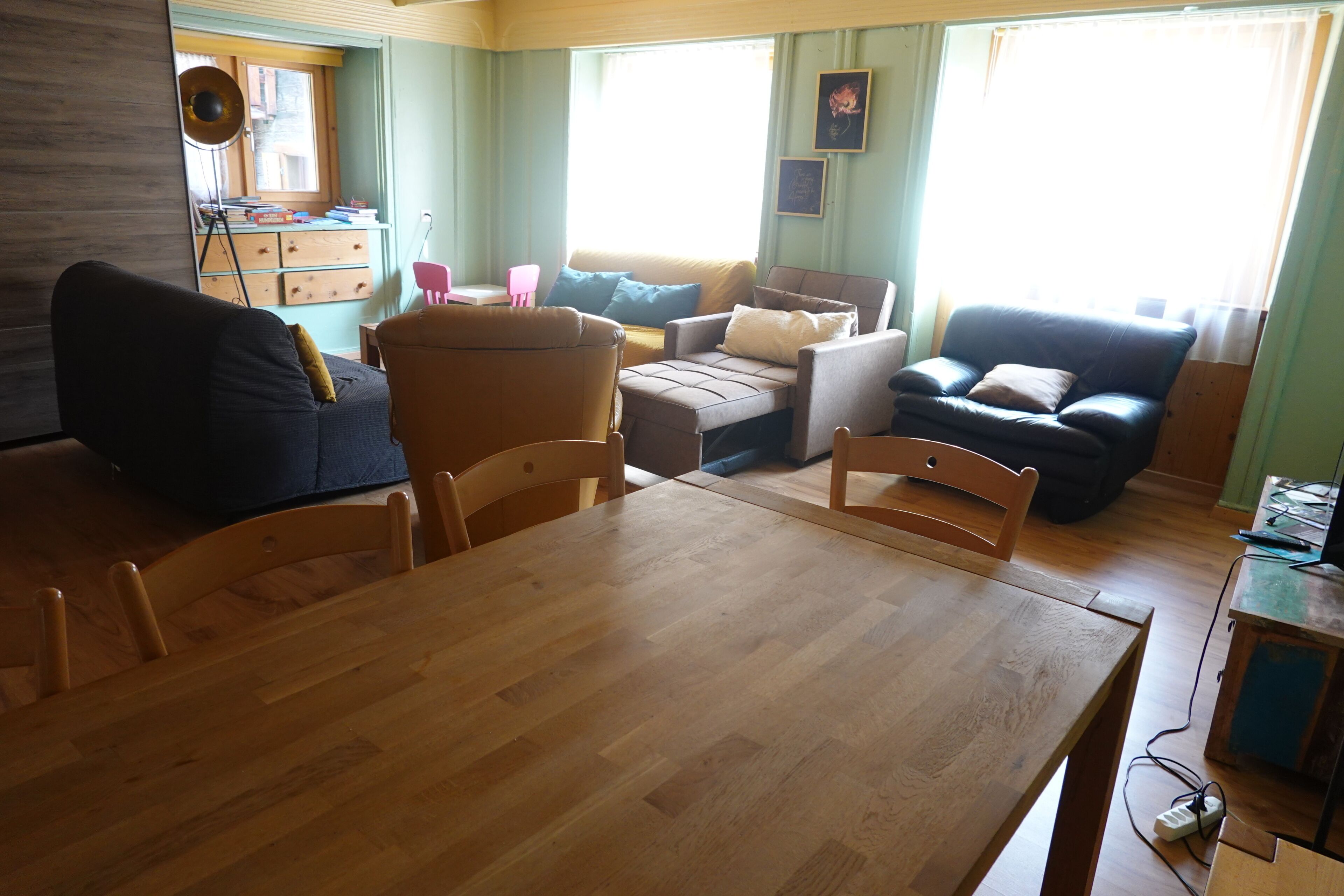Un salon comprenant une table à manger en bois, deux canapés, une table basse et une fenêtre avec des rideaux.