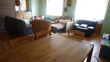 Un salon comprenant une table à manger en bois, deux canapés, une table basse et une fenêtre avec des rideaux.