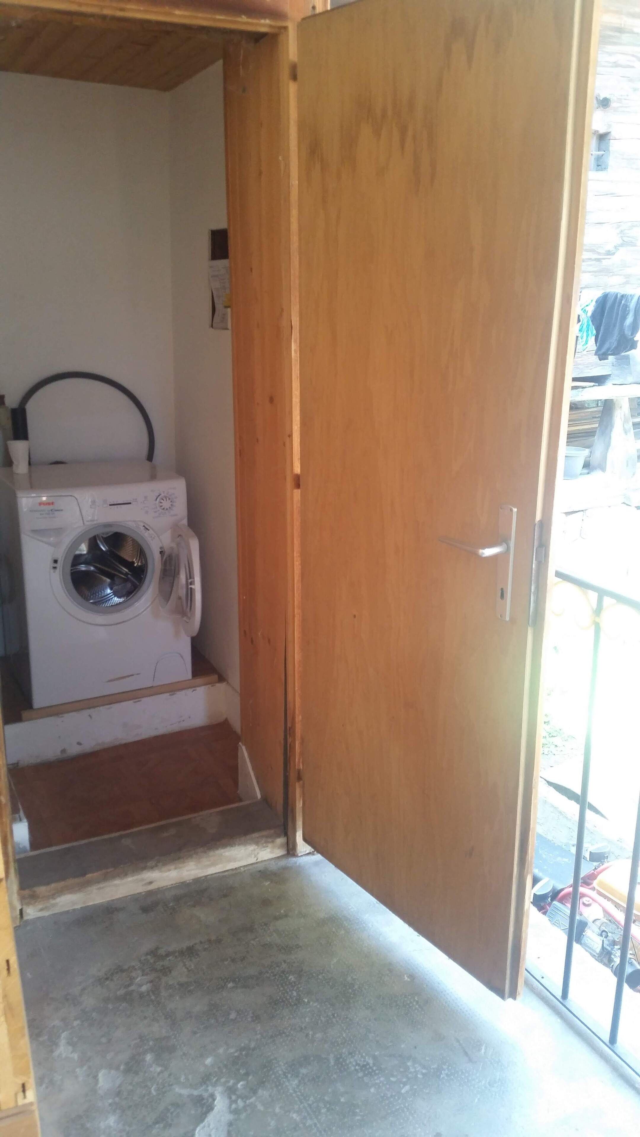 A laundry room with a washing machine and a door leading to a balcony.