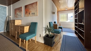 Ein modernes Wohnzimmer mit Holzboden, einem Essbereich mit Holztisch und -stühlen sowie einem großen Fenster, das für natürliches Licht sorgt.
