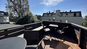 Eine Terrasse im Freien mit Tisch und Stühlen, umgeben von einer Holzterrasse und einem großen Baum.