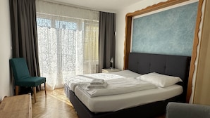 Ein Hotelzimmer mit Bett, Sessel, Schreibtisch und Blick ins Freie.